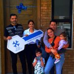 Familia recibiendo llave frente a su casa nueva.