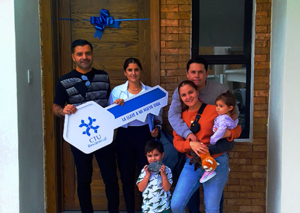 Familia recibiendo llave frente a su casa nueva.