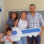 Familia feliz porque acaba de comprar casa. Papá, mamá, mujer adolescente sonrientes y niño saludando a la cámara.