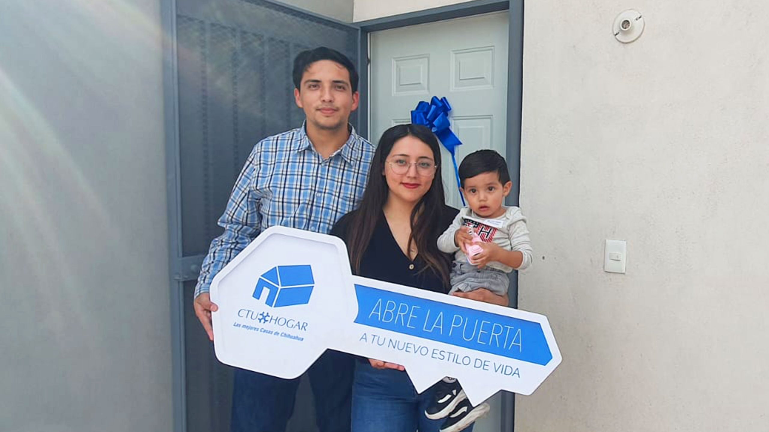 Familia de papá, mamá y niño de 2 años reunidos frente a la puerta de su casa nueva.