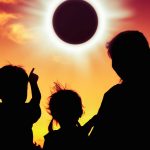 Familia de papá y dos niños menos de 5 años mirando al eclipse solar.