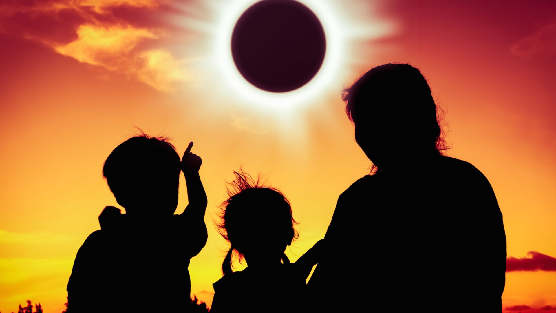 Familia de papá y dos niños menos de 5 años mirando al eclipse solar.