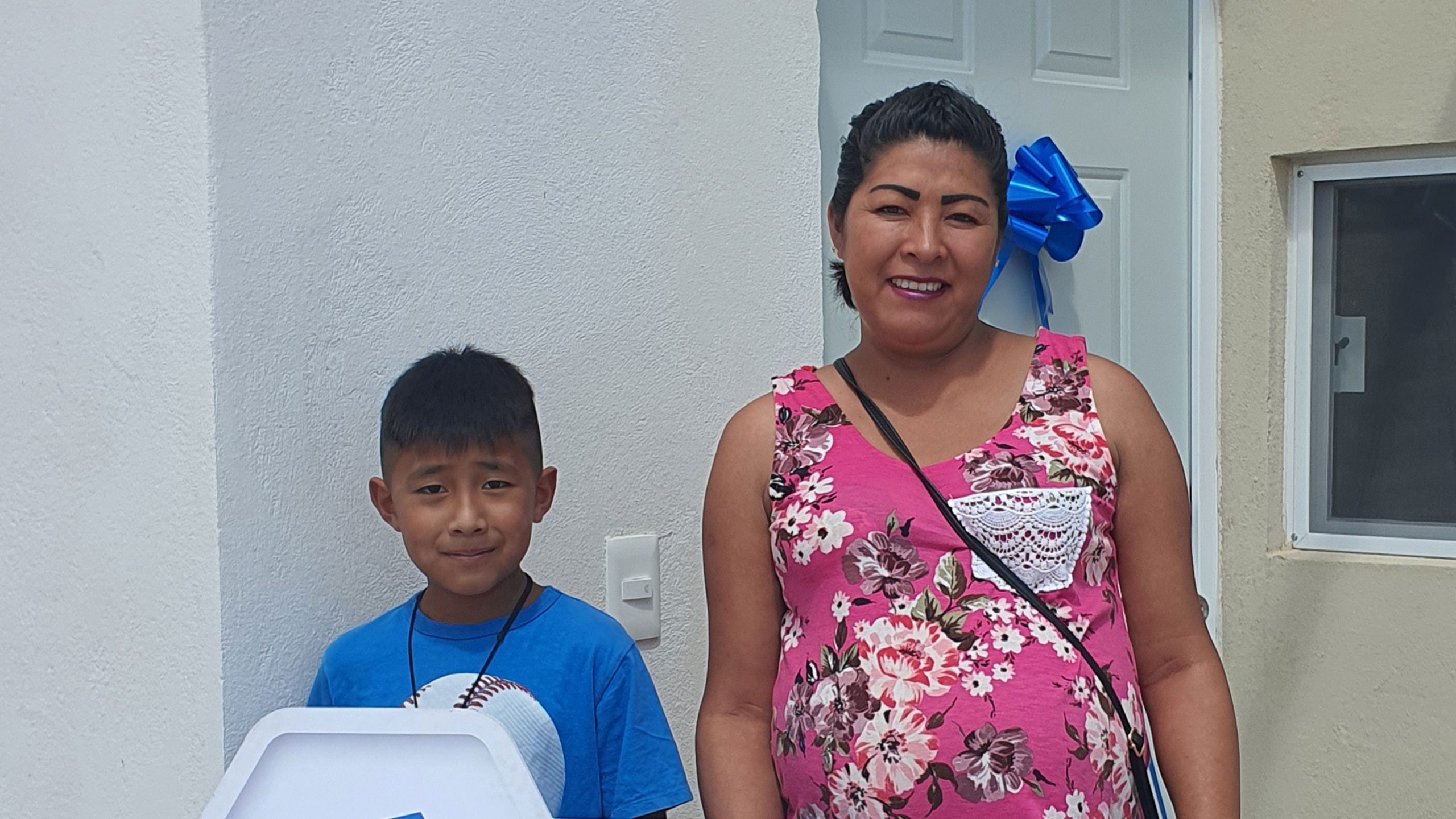 Mamá e hijo de cerca de 8 años recibiendo las llaves de su casa nueva.